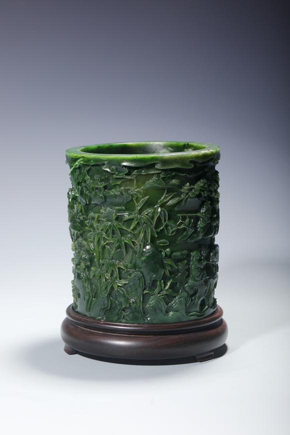 SEAVIEW AUCTIONS PTY LTDA Spinach Green Jade Cylindrical Brush Pot Carved with Mountain and Scholar Landscape, Wood Stand, China, 18th century