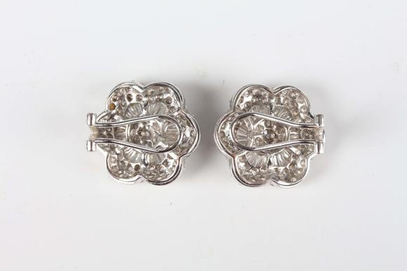 TooveysA pair of white gold and diamond earrings, each in a flowerhead shaped design, mounted with circular and tapered baguette cut diamonds, with post and