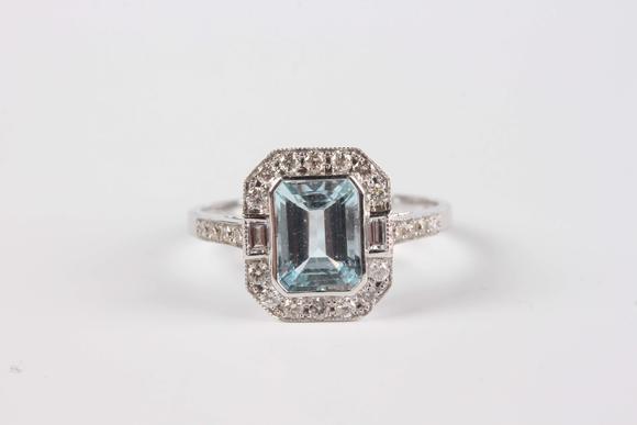 TooveysA white gold, aquamarine and diamond cluster ring, collet set with the cut cornered rectangular step cut aquamarine within a surround of baguette and
