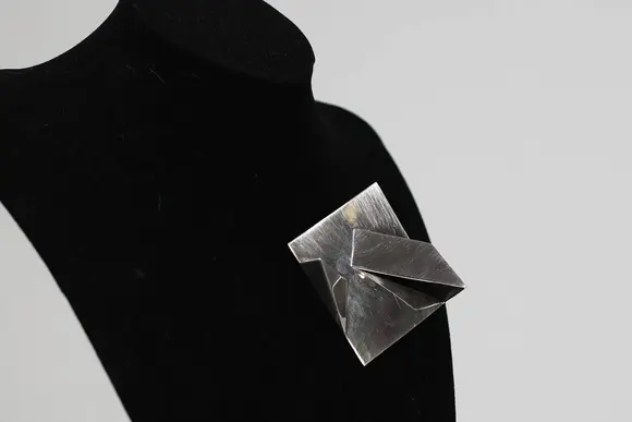 Goldfield Auction sarlsModernist brooch in 925/1000 silver, geometric shape with folded panels in relief, Italian work signed Carlo Lorenzetti, dated 1976.
Limited edition of 28, numbered and signed on the reverse, published by Galleria La Polena, Genoa.
A sculptural aesthetic characteristic of Italian research in the 1970s, in good overall condition.
Condition : Good
Height : 2 cm 
Width : 6 cm
Weight : 32,6 gr