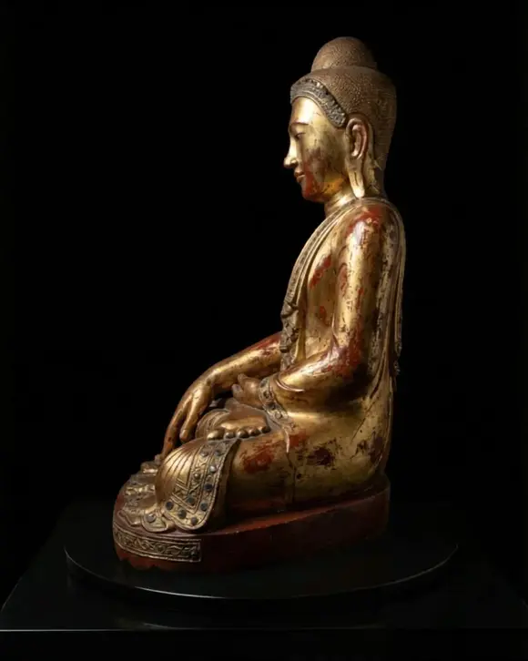 Bertolami Fine ArtBuddha figure in the lotus position. Lacquered and gilded wood with stucco and glass paste applications, set on a wooden and black lacquer base. Burma, Mandalay, 19th century.
