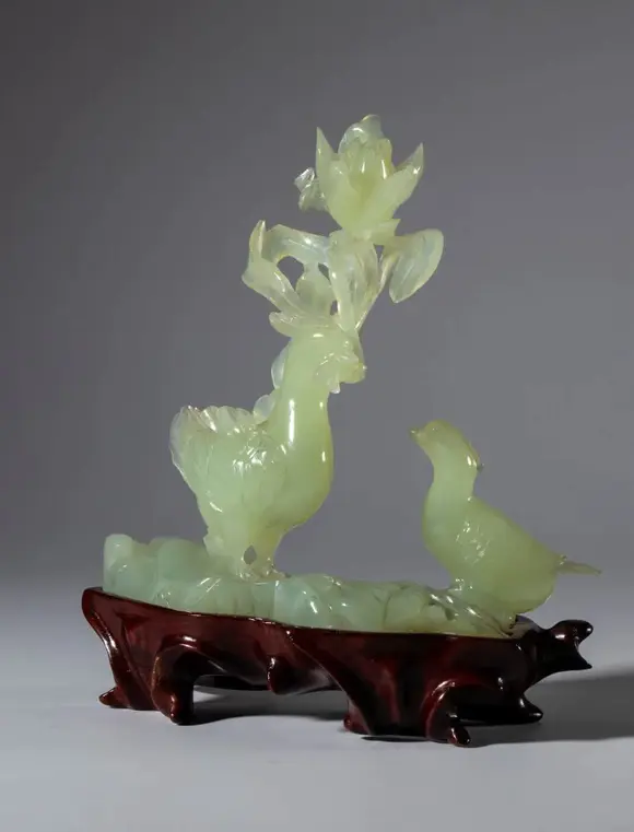 Bertolami Fine ArtGreen jade sculpture on a wooden base depicting a pair of birds and a large flower. China, 20th century.