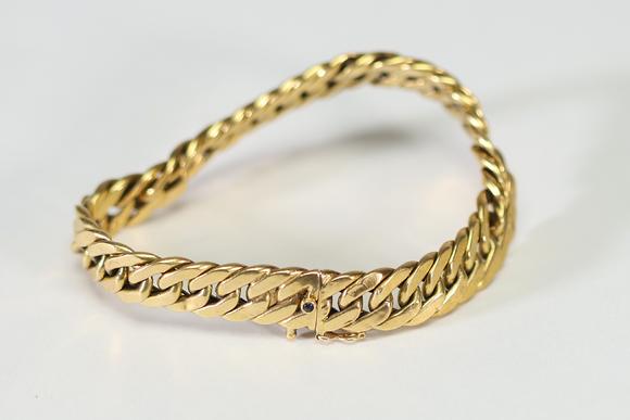 Goldfield Auction sarlsBracelet gourmette ? Caplain Paris ? en or jaune, composé de larges maillons plats et articulés, fermoir mousqueton orné d’un cabochon de saphir bleu