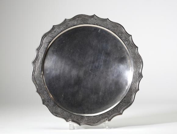 Goldfield Auction sarlsAssiette dite volante en argent massif, travail liégeois daté 1724, de forme circulaire à bord contourné et légèrement festonné. Elle repose sur trois