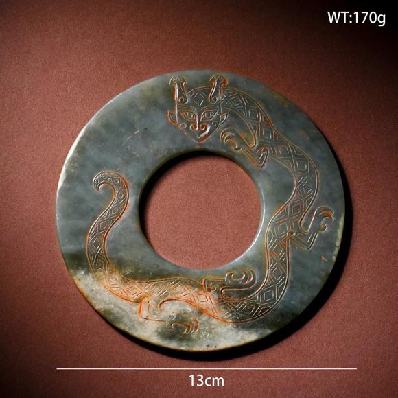 HUNG YUN ZHAI AUCTION HOUSE INCPre-Ming Dynasty Cinnabar-Infiltrated Dragon- Pattern Jade Bi Disc