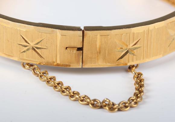 TooveysA gold circular hinged bangle with facet cut decoration, detailed ‘