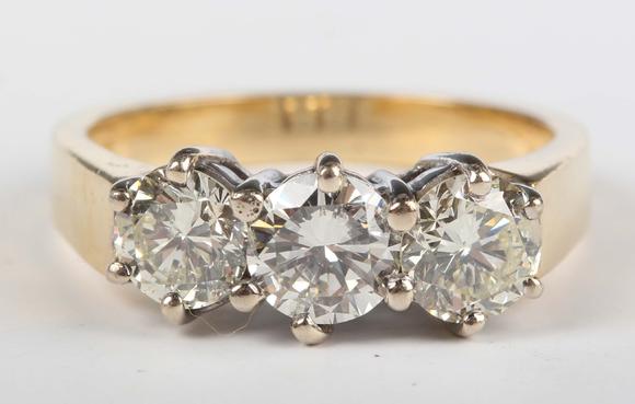 TooveysAn 18ct gold and diamond three stone ring, claw set with a row of ci