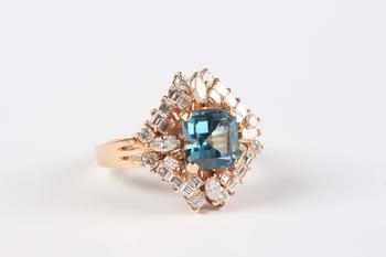 A gold, blue topaz and diamond cluster ring, claw set with the cut cornered square cut blue topaz within a surround of marquise, baguette and circular