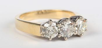 An 18ct gold and diamond three stone ring, claw set with a row of ci